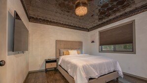 Un dormitorio con cama, mesita de noche y lámpara en el techo.