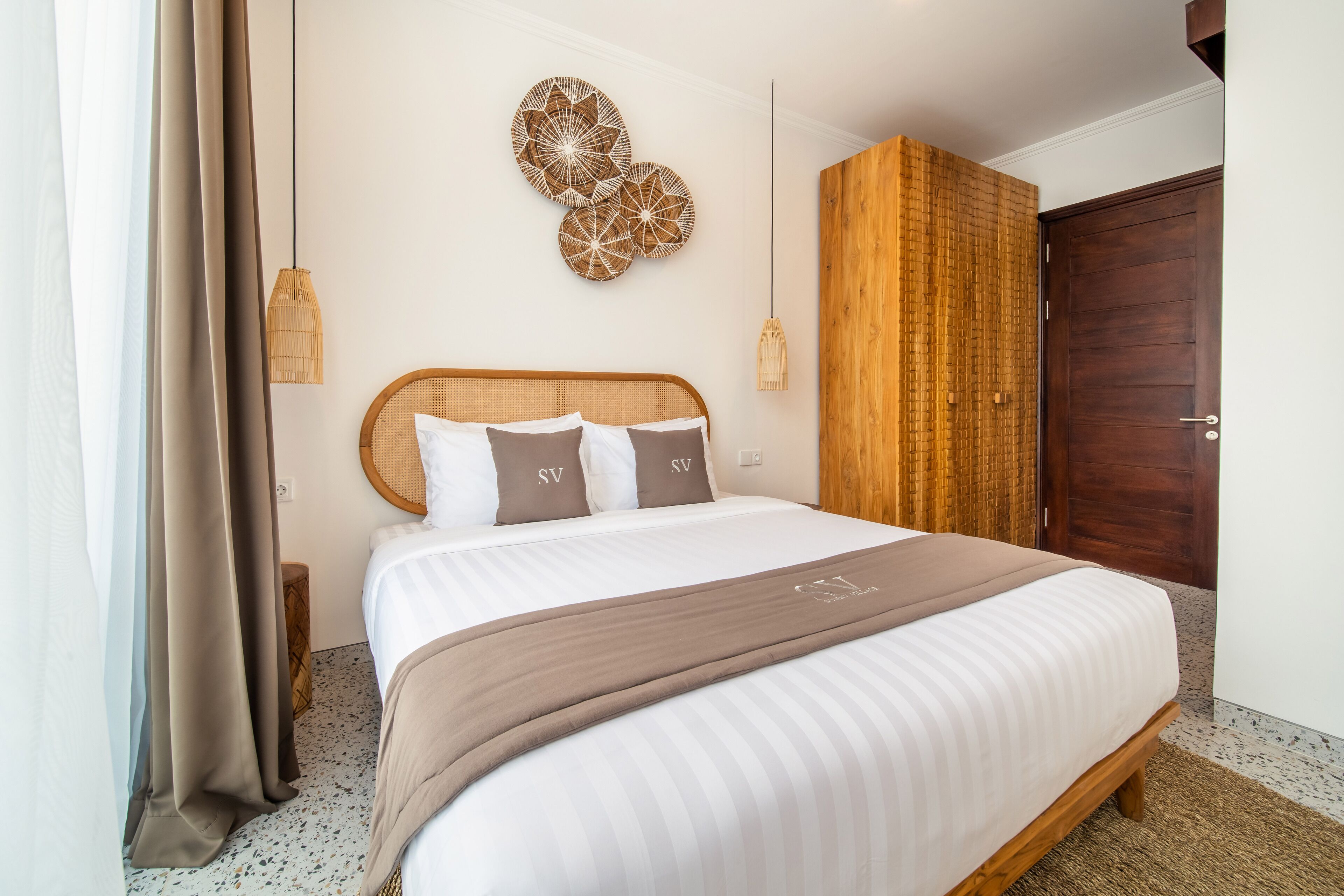 A neatly made bed with a headboard, a decorative wall piece, and a wooden wardrobe.