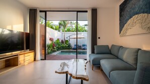 Uma sala de estar moderna com uma televisão de tela plana grande, um sofá cinza e uma mesa de centro de madeira única.