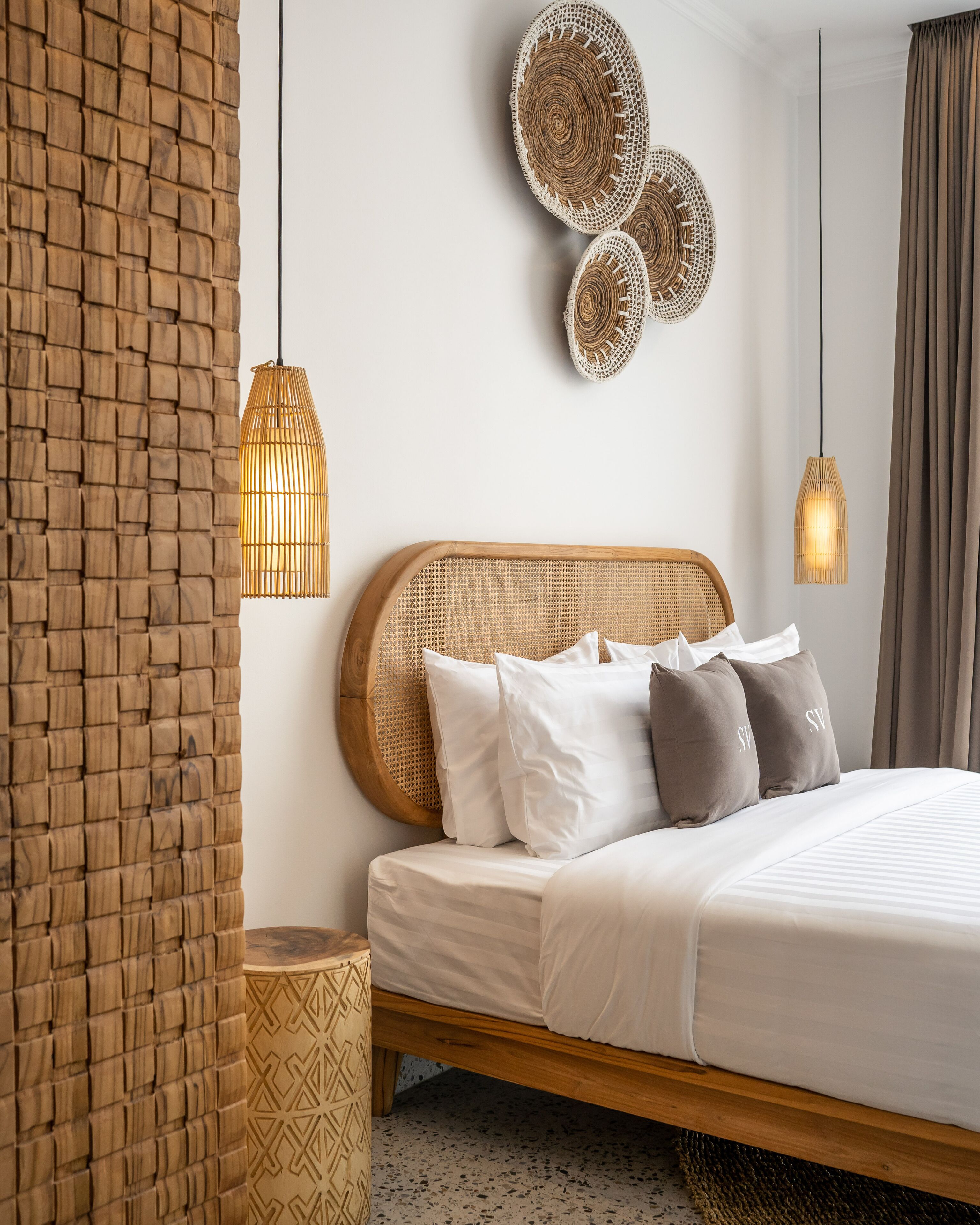 A modern bedroom with a wooden headboard, white bedding, and woven wall decor.