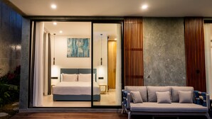 Quarto moderno com uma cama grande, um sofá e uma porta de vidro deslizante para uma varanda.