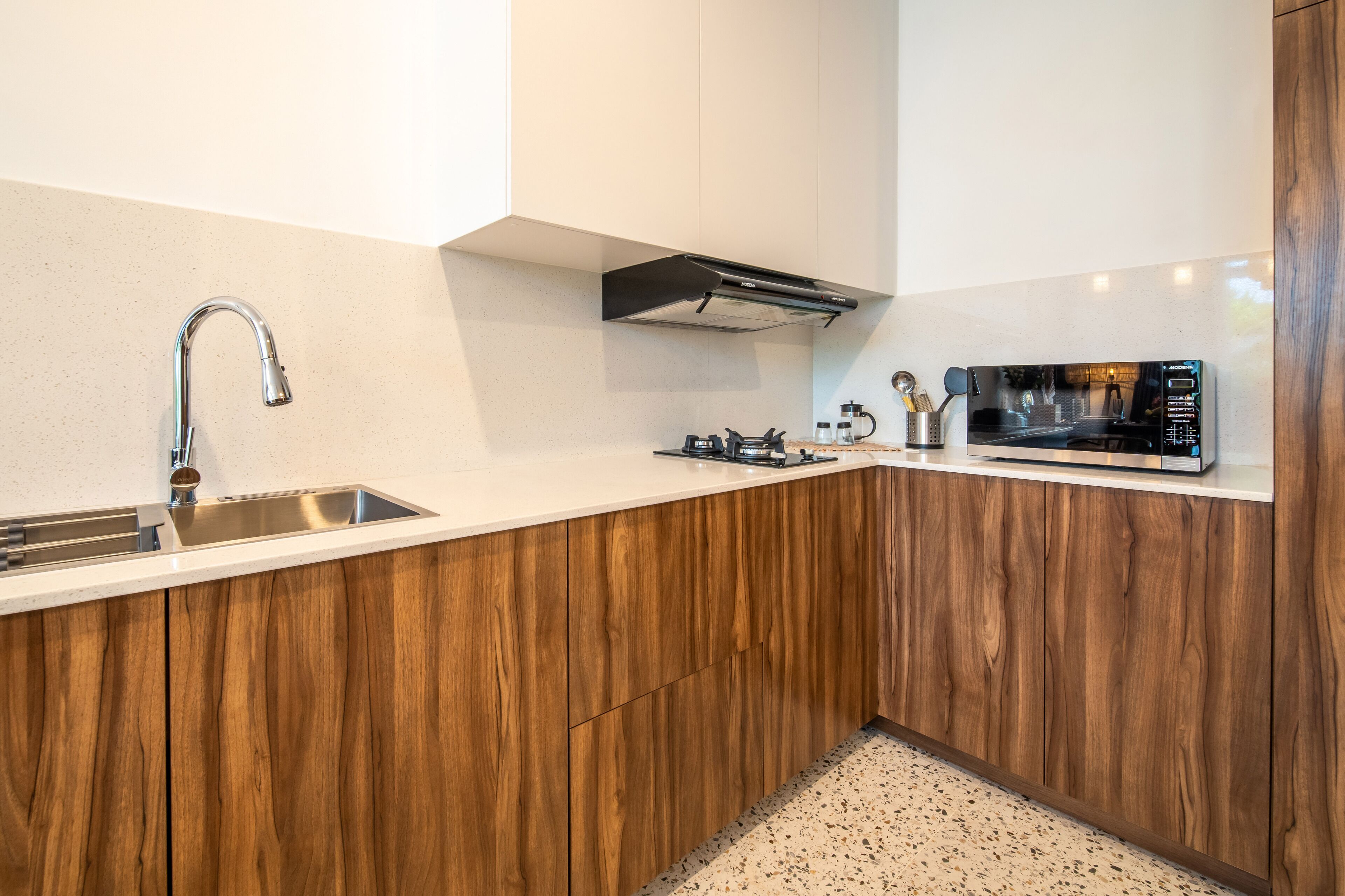 Eine moderne Küche mit Spüle aus Edelstahl, Holzschränken, einer eingebauten Mikrowelle und einer Dunstabzugshaube.