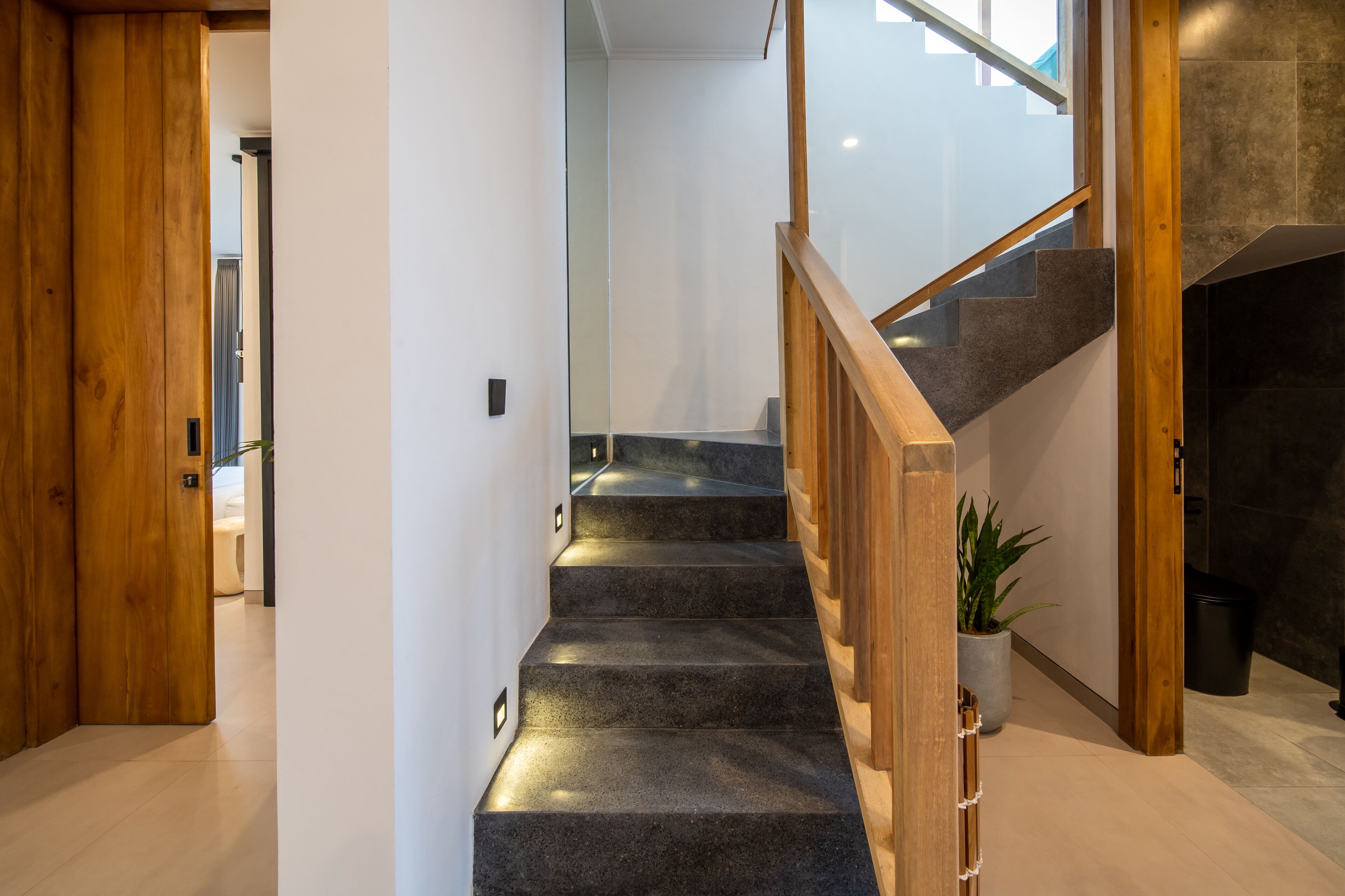 A modern staircase with wooden railings and a potted plant.