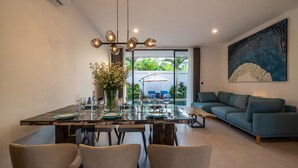 Uma sala de jantar moderna com mesa de vidro, quatro cadeiras e um vaso de flores.