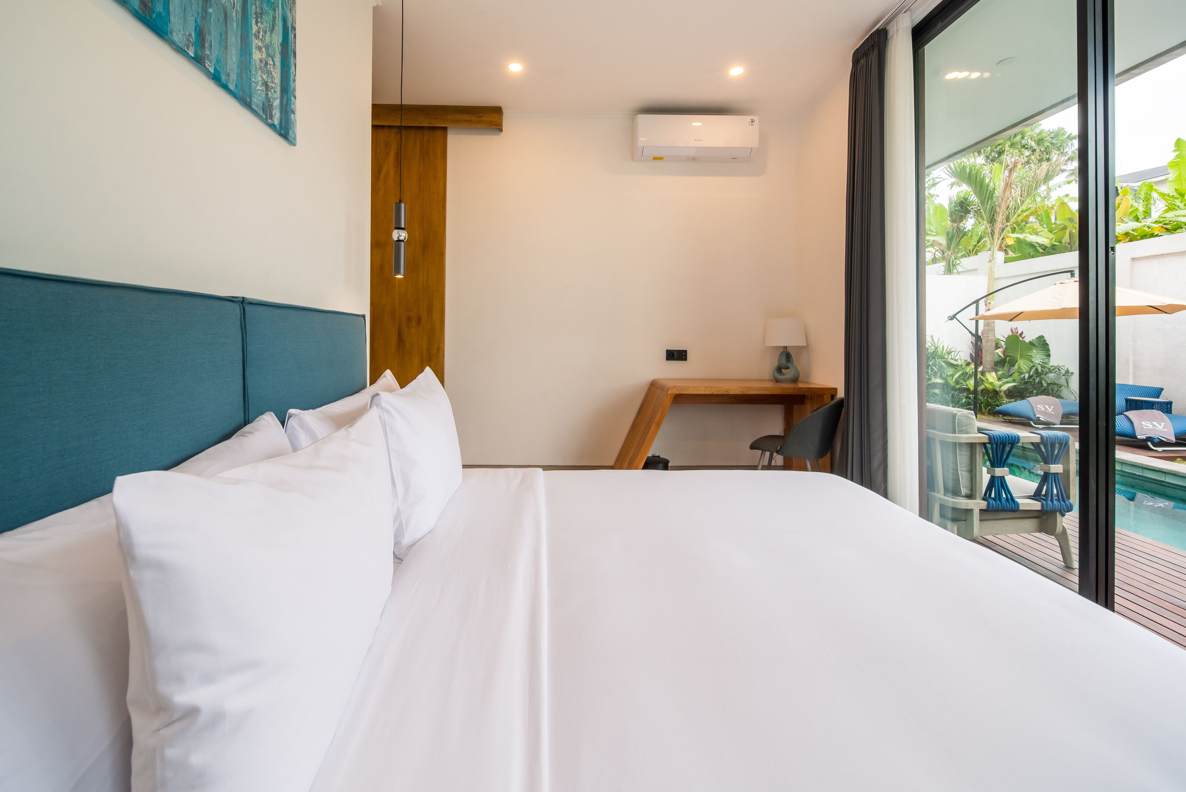 A hotel room with a large bed, a desk, and a view of an outdoor pool area.