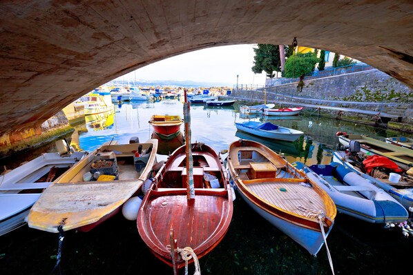 A view of boats docked under a bridge, with calm water and a clear sky.