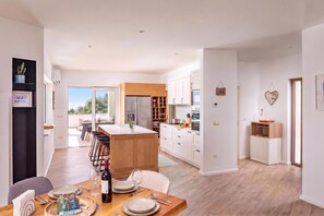 Een moderne keuken met een centraal eiland, witte kasten en een eethoek met een houten tafel gedekt voor twee personen.
