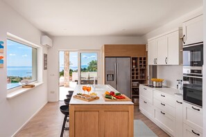 A modern kitchen with a central island, built-in appliances, and a view to the outdoors.