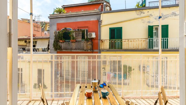 Ein Balkon mit Blick auf ein Gebäude mit einer grünen Kuppel und einer gelben Fassade.