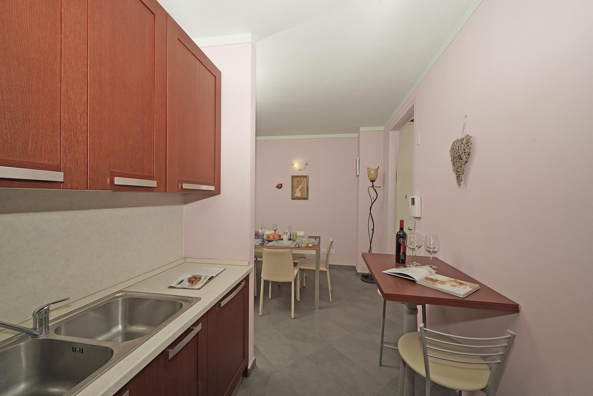 A compact kitchen with a double sink, wooden cabinets, and a dining area with a table and chairs.