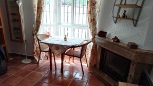 Un área de comedor con una mesa y sillas, una chimenea y un ventanal con cortinas.
