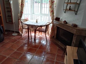 Un área de comedor con una mesa y sillas, una chimenea y un ventanal con cortinas.