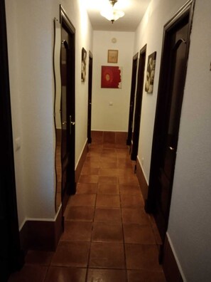A hallway with tiled flooring and dark wooden doors.