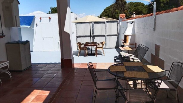 Eine Außenpatio mit Tisch, Stühlen, einem Grill und Blick auf das Meer.