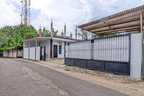 Ein geschlossenes Wohngebiet mit einem kleinen Haus, einem Metallzaun und einem hohen Sendeturm im Hintergrund.