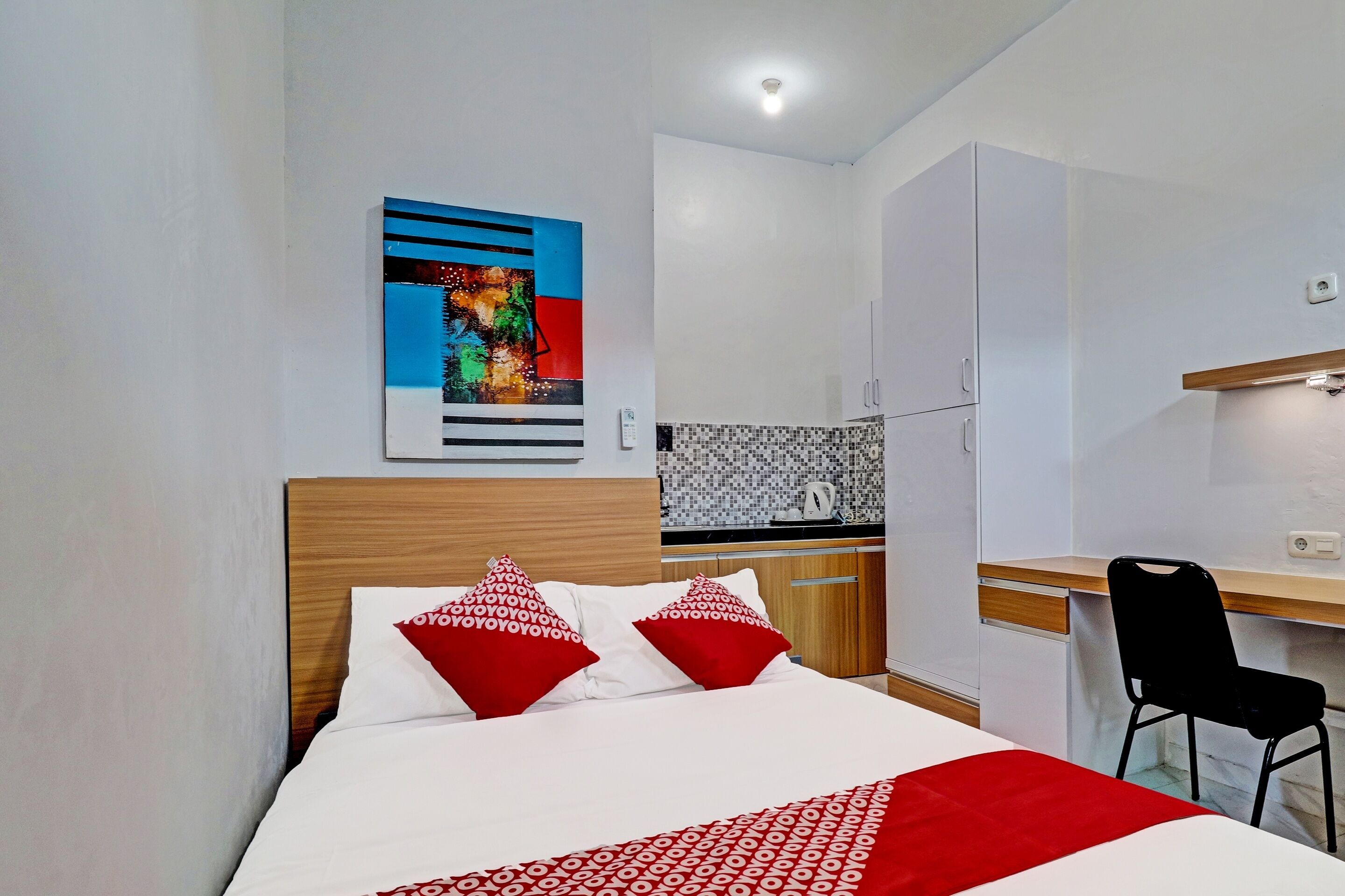 Una habitación de hotel con cama, escritorio, silla y kitchenette.