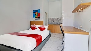 Een moderne slaapkamer met een bed, bureau en kitchenette.