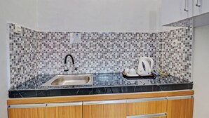 Een keuken met een betegelde spatwand, een spoelbak en houten keukenkastjes.