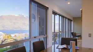 A modern room with large windows, a dining table, and chairs.