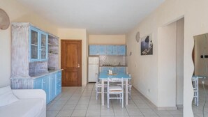 A compact living space with a kitchenette, a dining area, and a white sofa.