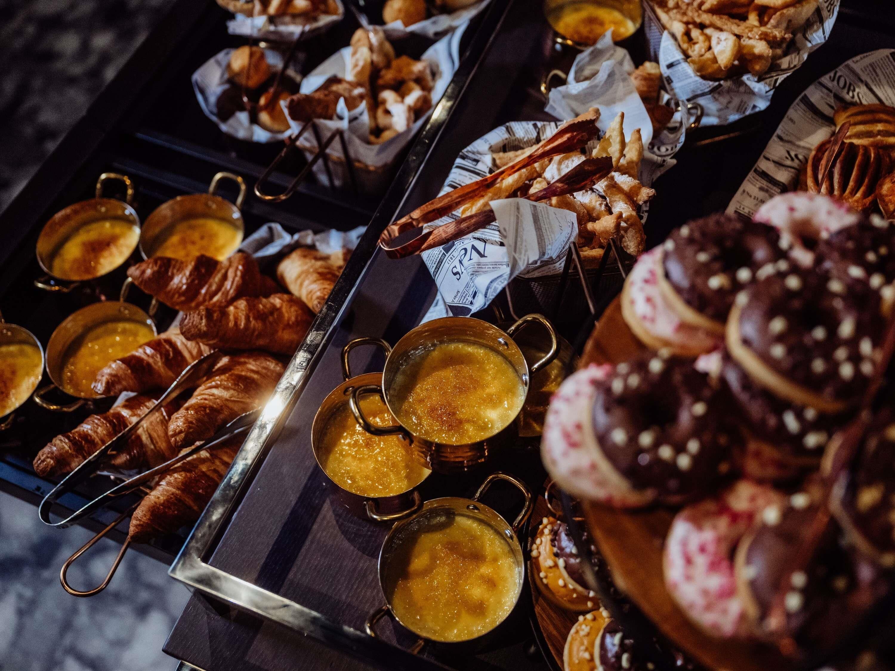 A buffet with various baked goods and hot beverages.