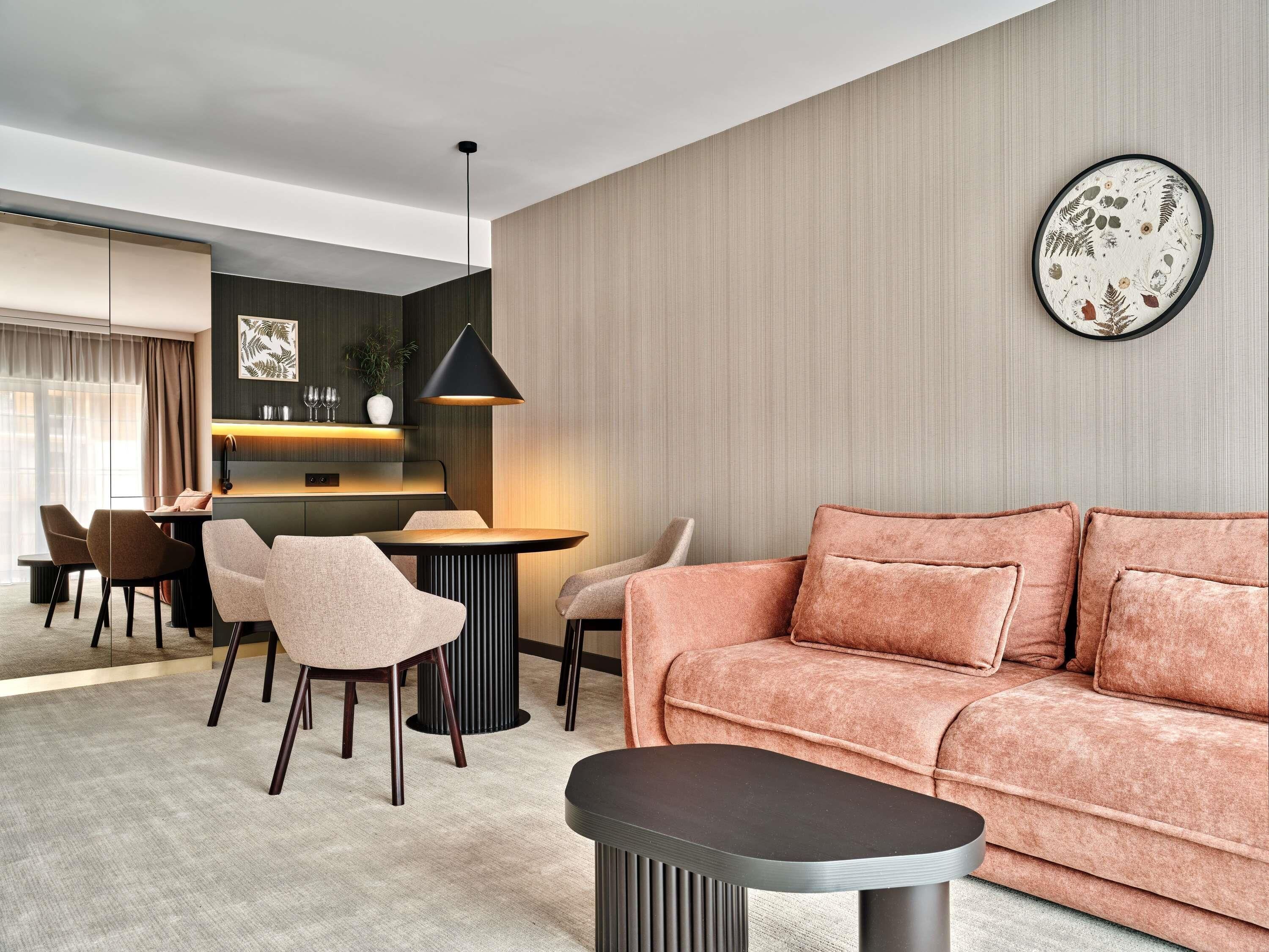 A modern living room with a sofa, chairs, a dining area, and a kitchen.