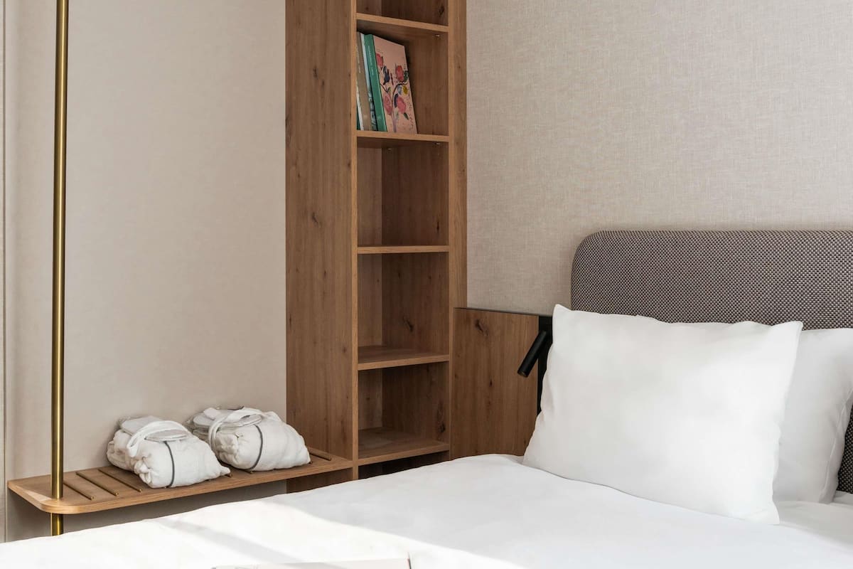 Quarto de hotel com uma cama, um guarda-roupa de madeira e uma prateleira com toalhas.