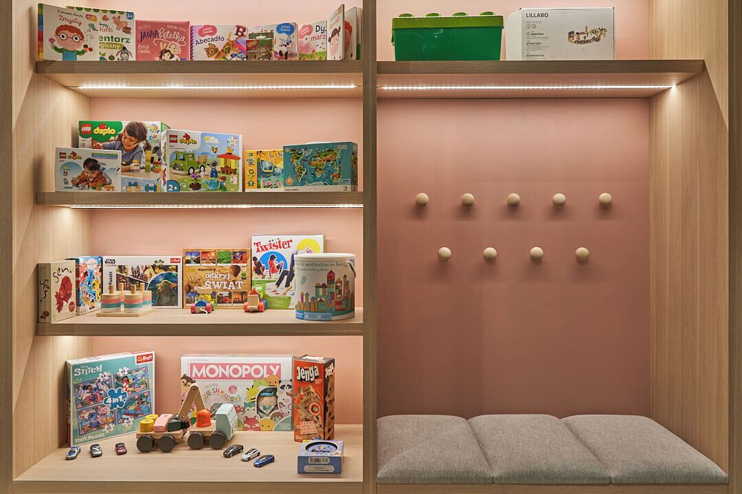 A children's play area with shelves of toys and games, including LEGO sets and board games.