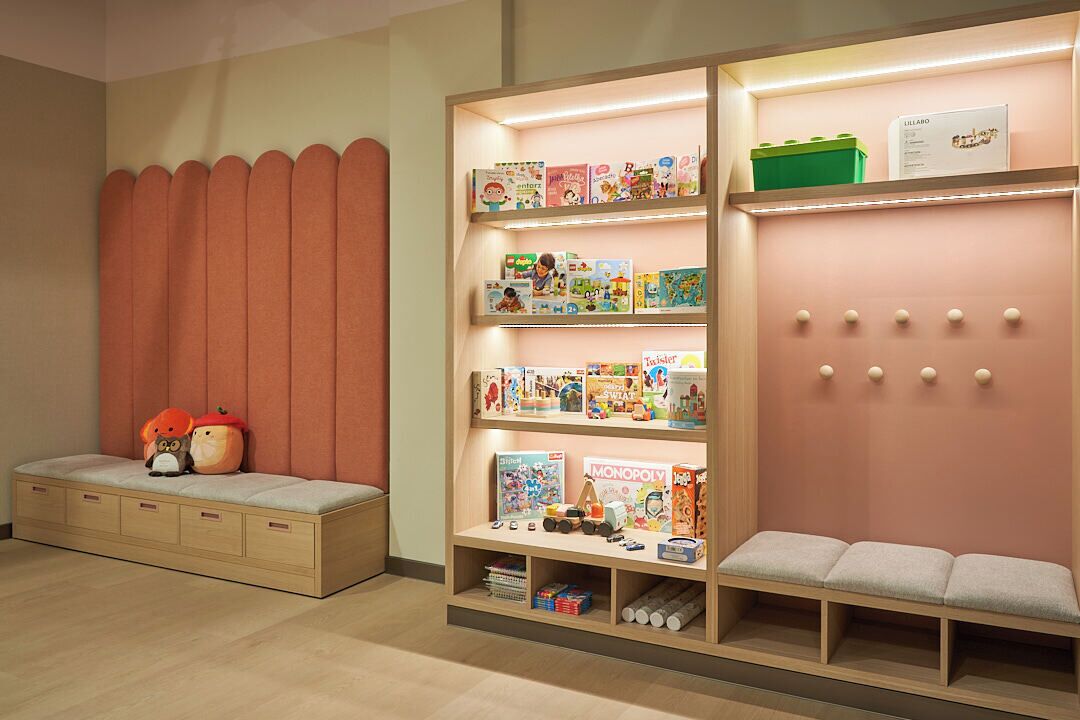 A children's play area with a bookshelf, seating, and storage drawers.
