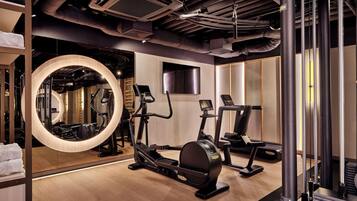 A gym with exercise equipment, a large mirror, and a TV screen.