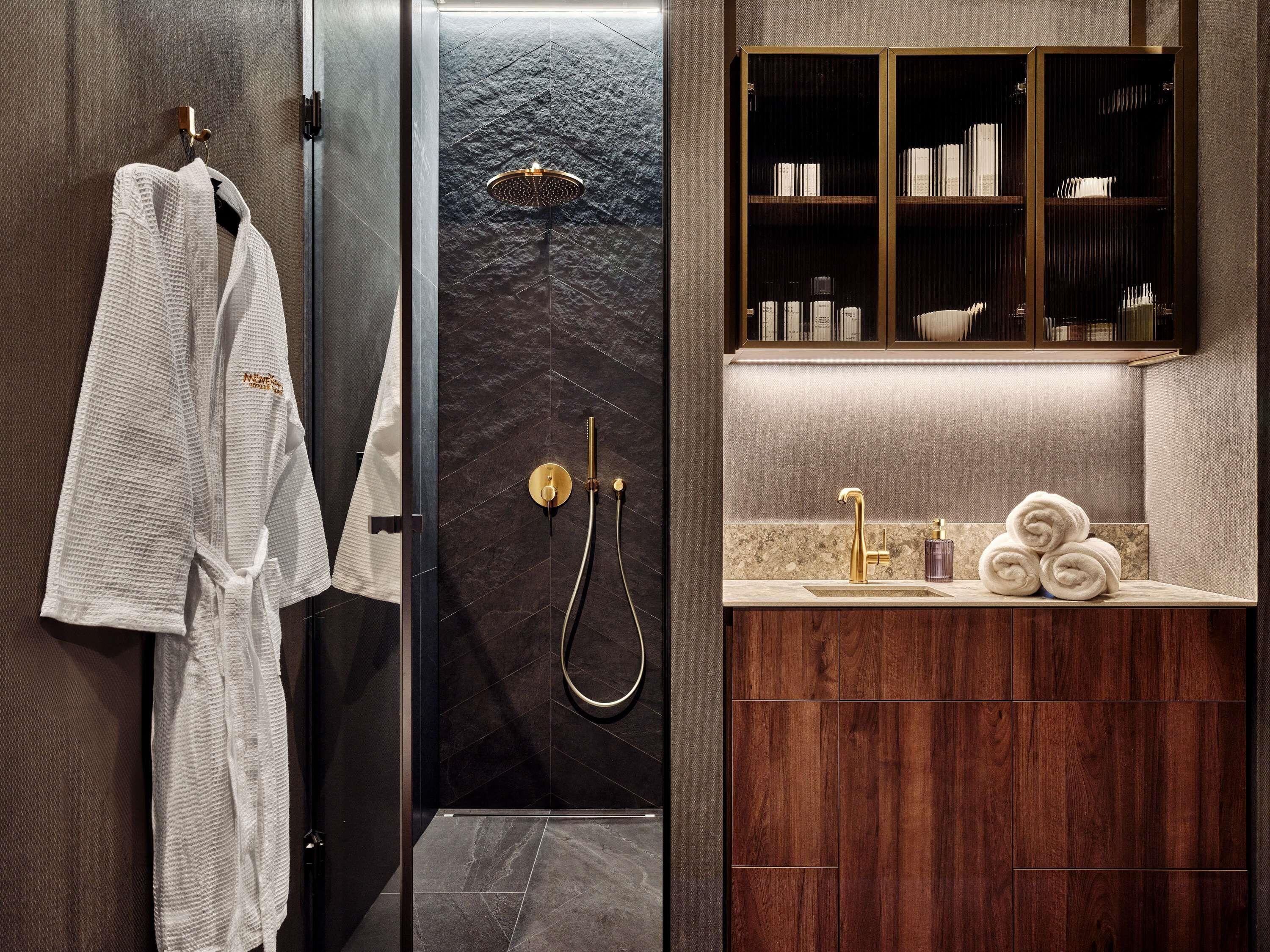 A modern bathroom with a glass-enclosed shower, a wooden vanity with a sink, and a towel rack with white towels.