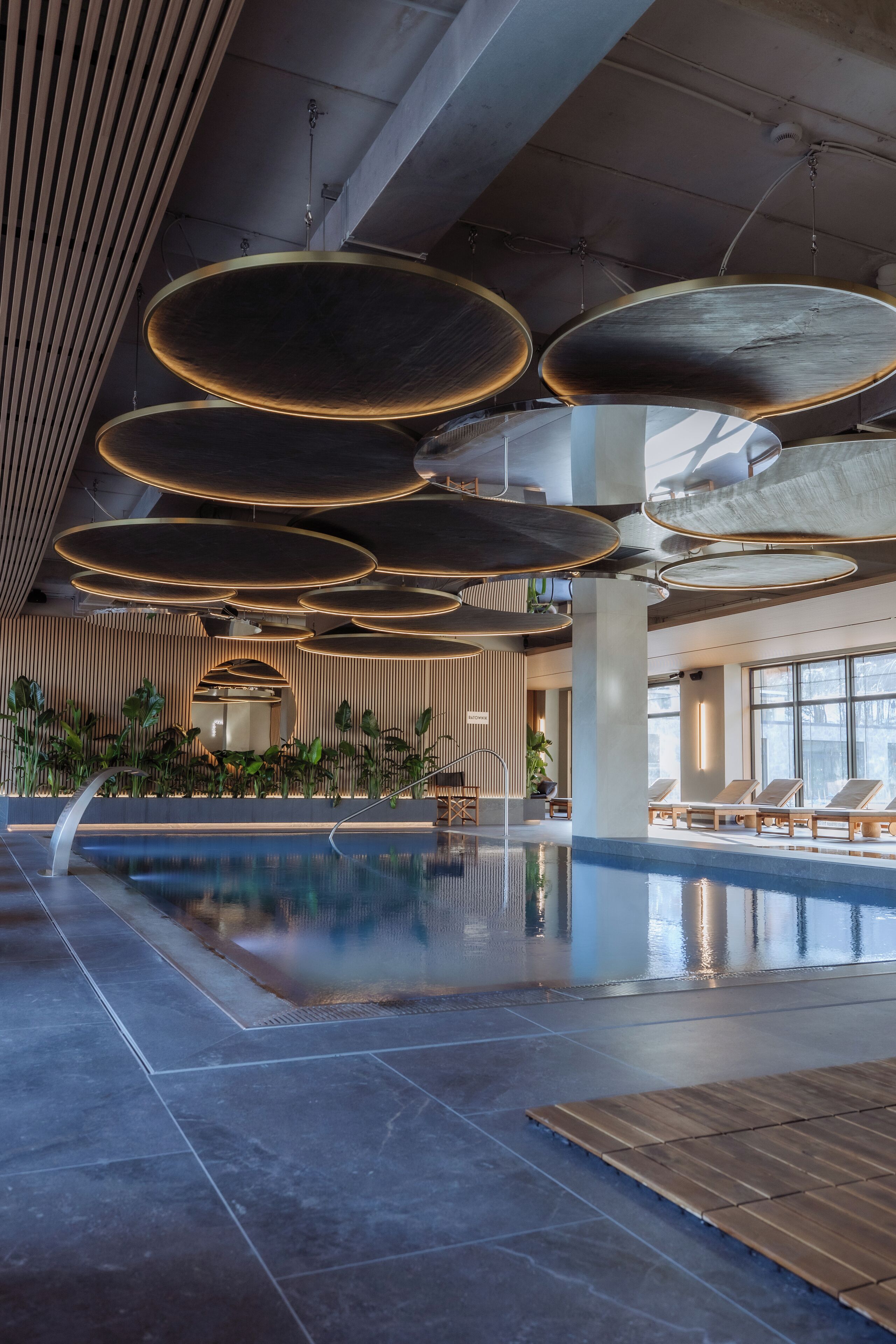 A spacious indoor swimming pool with modern lighting fixtures and lounge areas.