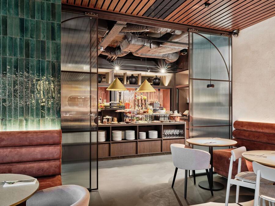 Un espace bar moderne doté d’un comptoir central, de sièges et de luminaires suspendus.