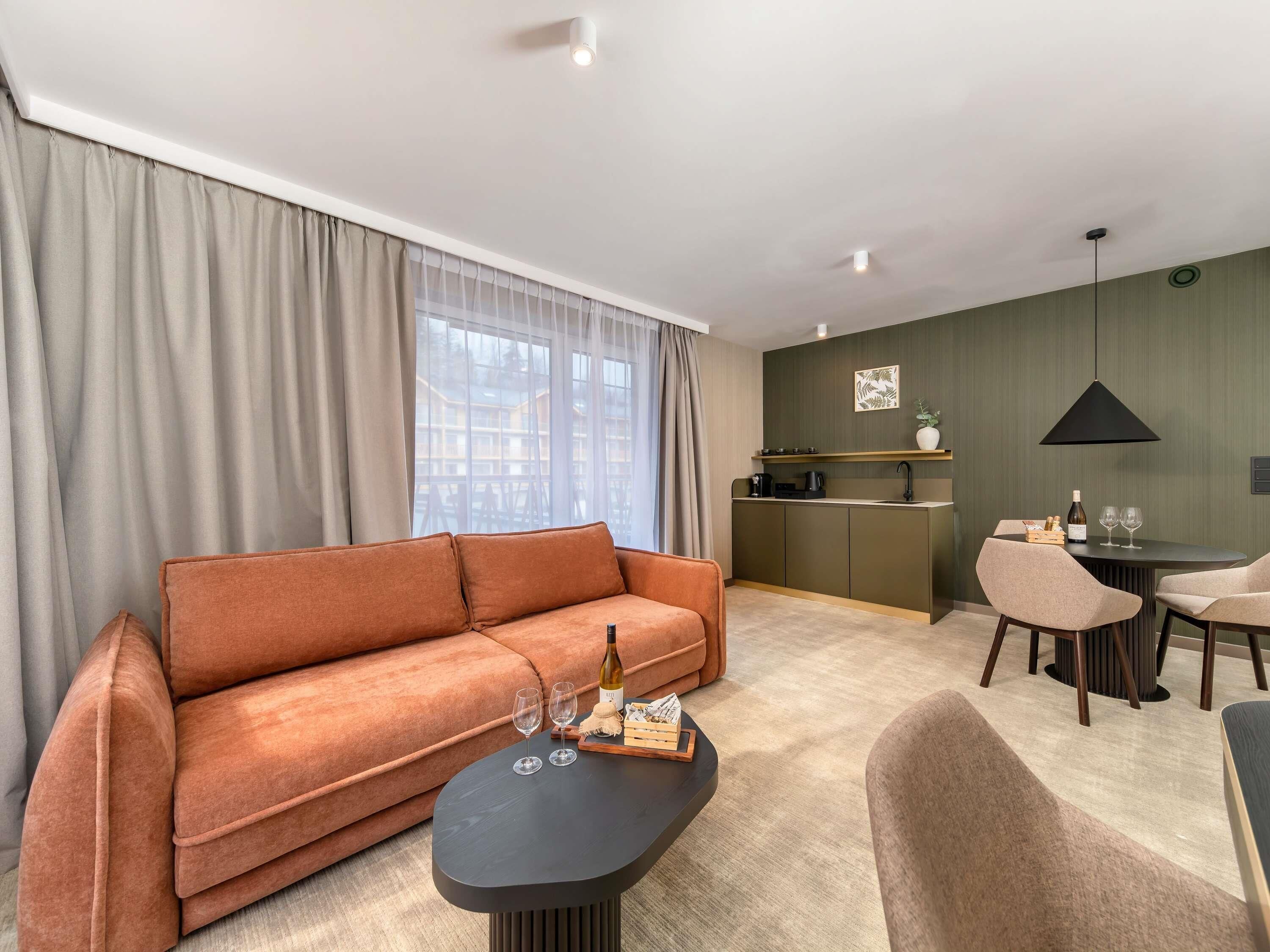 A modern living room with a sofa, a coffee table, and a dining area with chairs and a small kitchen.