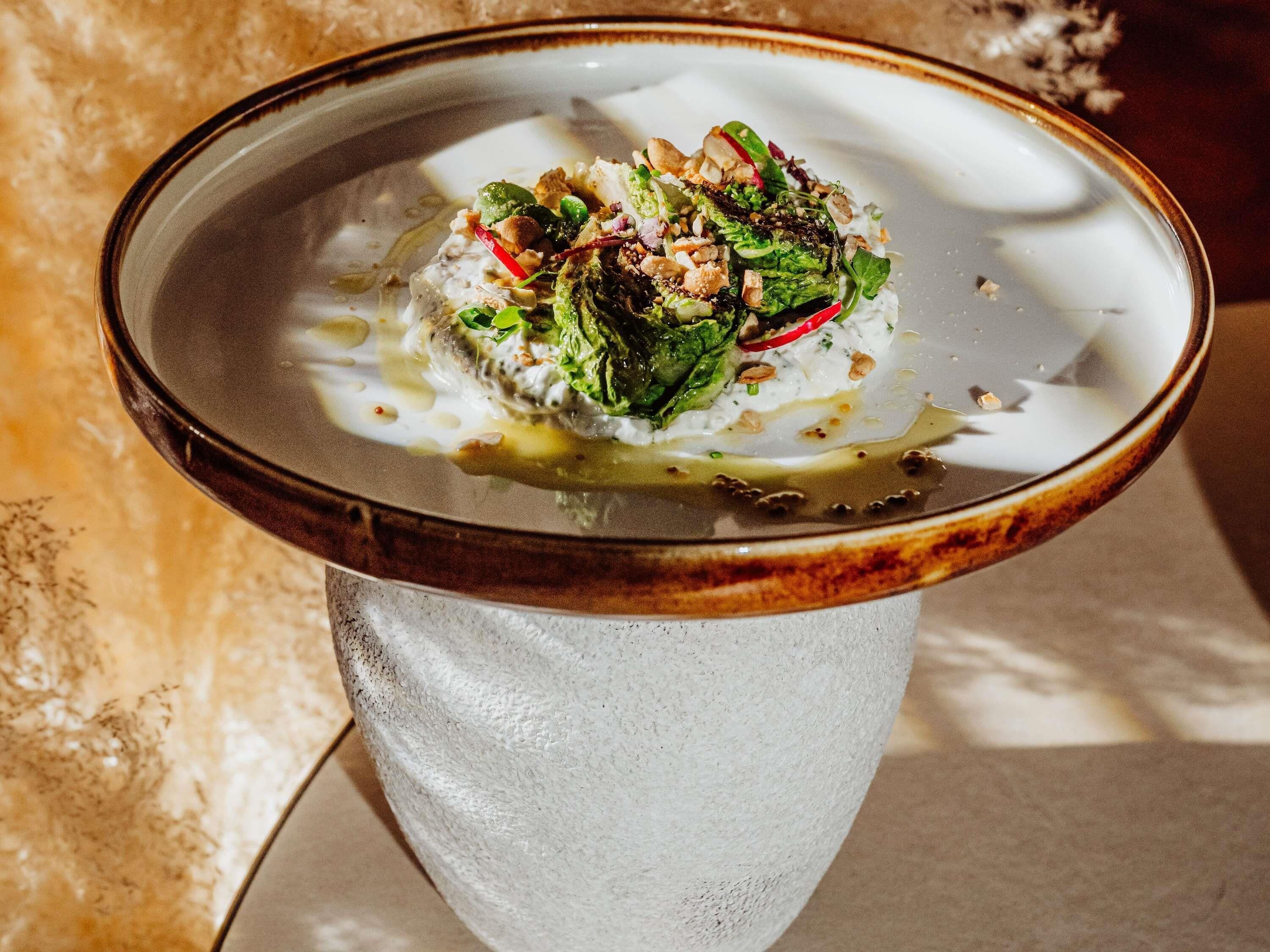 A dish on a ceramic plate with a rustic rim, placed on a textured surface.