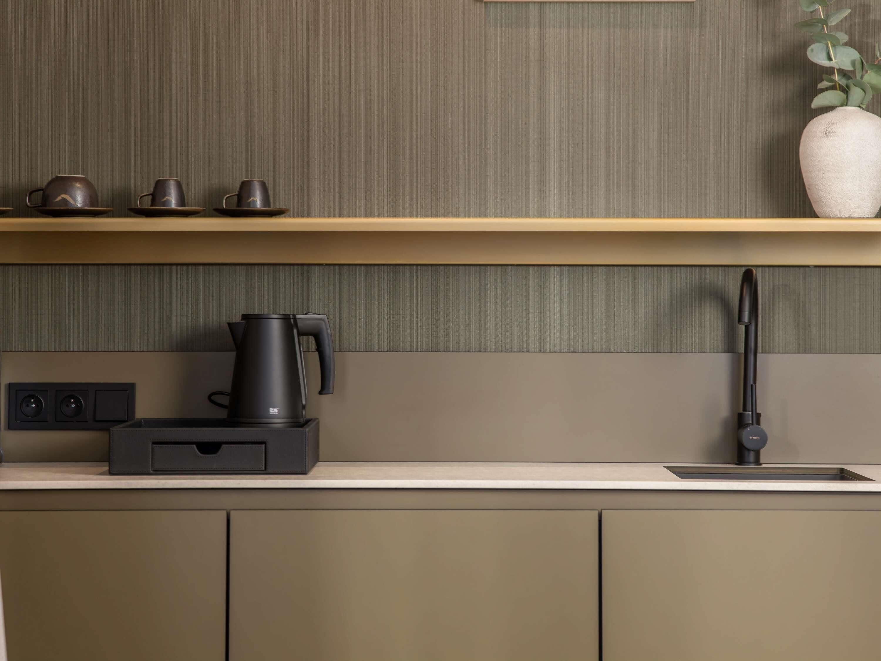 A modern kitchen with a built-in coffee maker, a sink, and a plant on the countertop.