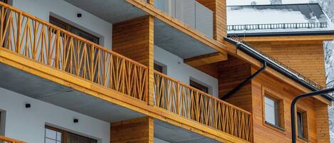 A multi-story building with wooden balconies and large windows.
