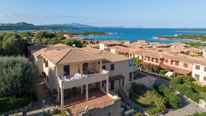 Complejo de villas costeras con techos de teja y un patio central, con vistas al mar.