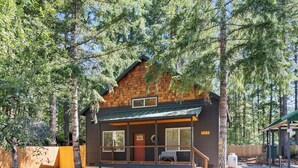 A cabin with a porch, large windows, and a number '125' sign.