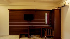 A room with a wooden desk, a television mounted on the wall, and a wardrobe. - Hotel Shalimar Residency (Kanayannur)