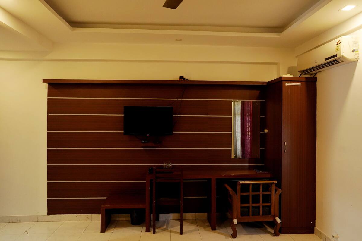 Ein Zimmer mit einem Holztisch, einem an der Wand montierten Fernseher und einem Kleiderschrank.