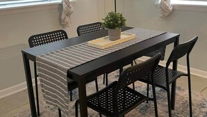 Ein Essbereich mit Tisch, Stühlen, einer Lampe und Bildern an den Wänden.
