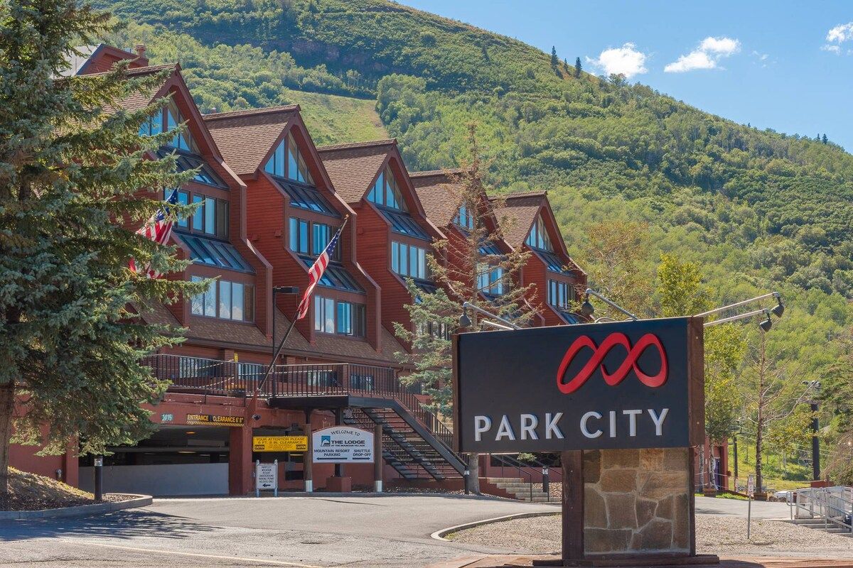Un refugi amb muntanyes al fons, un cartell que diu 'Park City' i un cel serè.