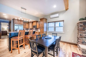 A modern kitchen with wooden cabinets, a central island, and a dining area with a large table and chairs.