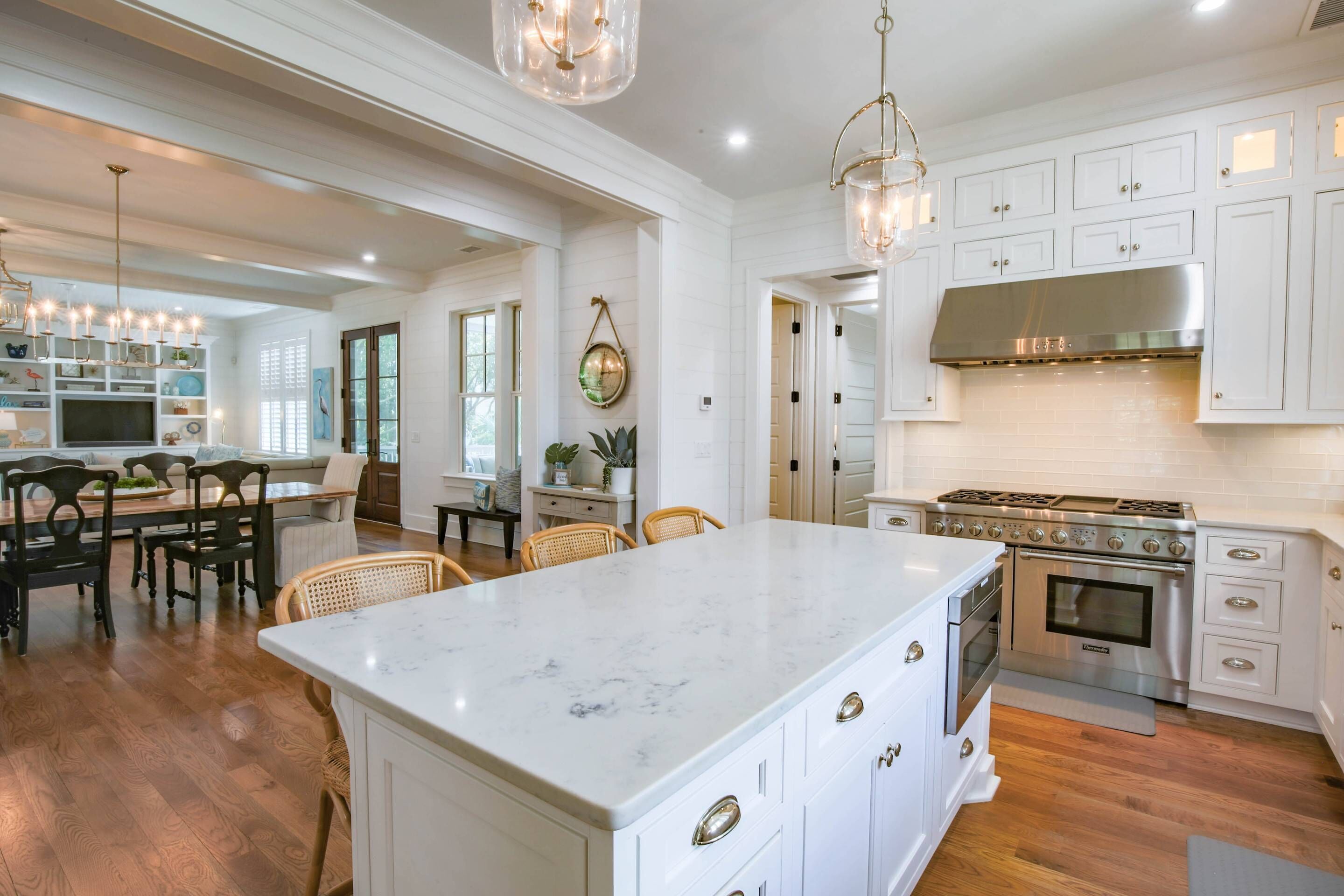 A spacious kitchen with white cabinetry, a large island, and a stainless steel range hood.