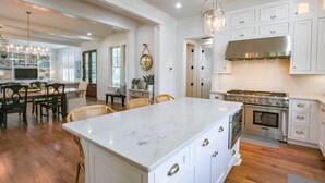 A spacious kitchen with white cabinetry, a large island, and a stainless steel range hood. - Upscale, Custom Home 3 Doors From Beach w/ Private Pool, Hot Tub & Screened Porch, Bunk Room & Den (Isle of Palms)