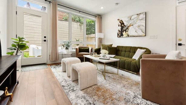 A modern living room with a sofa, ottomans, a coffee table, and a ceiling fan.