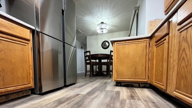 Een keuken met houten kastjes, roestvrijstalen apparatuur en een eethoek met een tafel en stoelen.