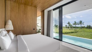 Un dormitorio moderno con una cama grande, paredes de paneles de madera, una lámpara colgante y vistas a una piscina y vegetación.