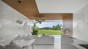 Una cocina moderna con una isla grande, armarios blancos y vistas a un paisaje verde.